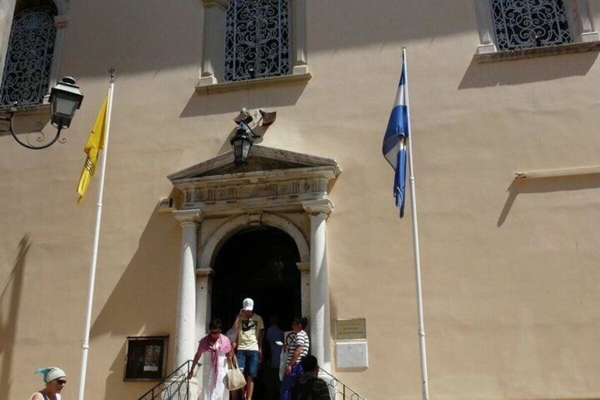 A building with a classical entrance, two flags, and a street lamp. 2