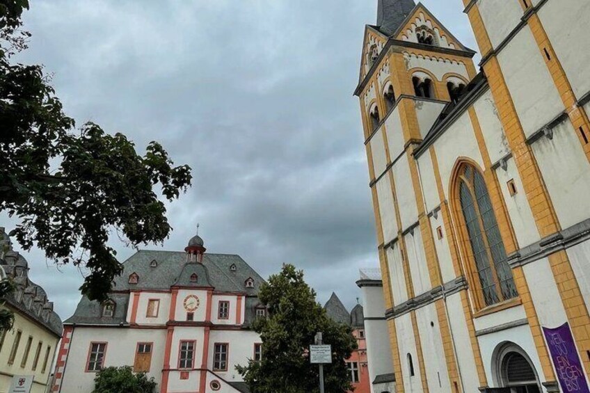 A historic church with a bell tower, a red-roofed building, and a cloudy sky. 3