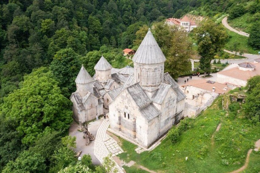 A historic stone church with multiple domes surrounded by lush greenery. 3