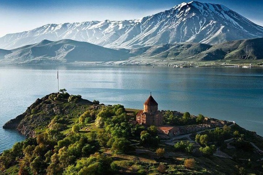 A church on a small island surrounded by a lake and a mountain range. 4