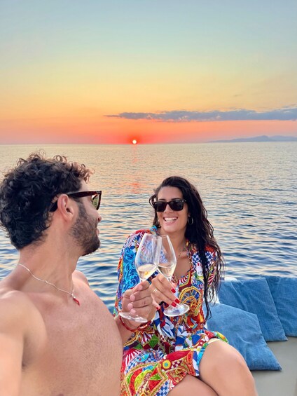 Two people toasting with wine glasses on a boat at sunset. 1