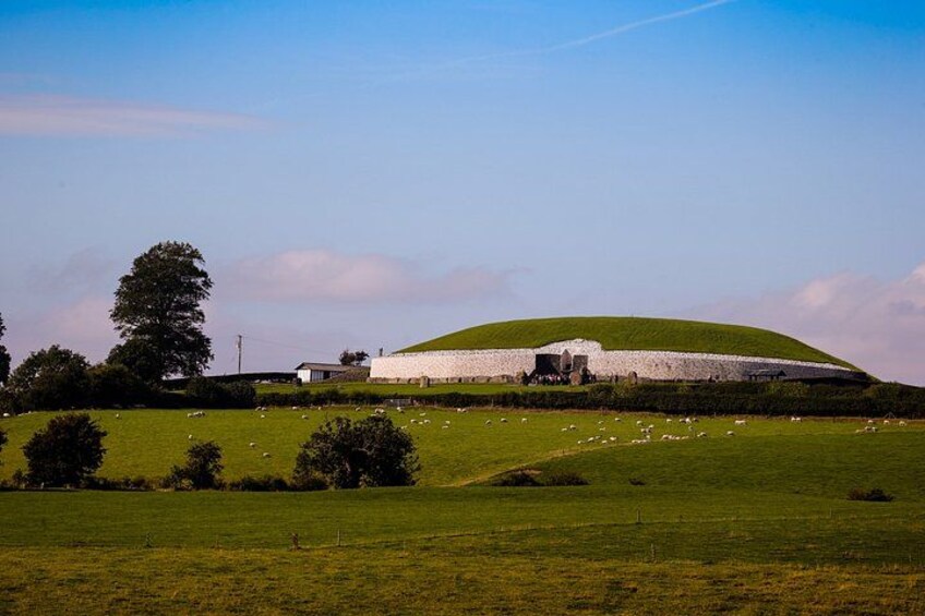A green field with a white building and a hill. 1