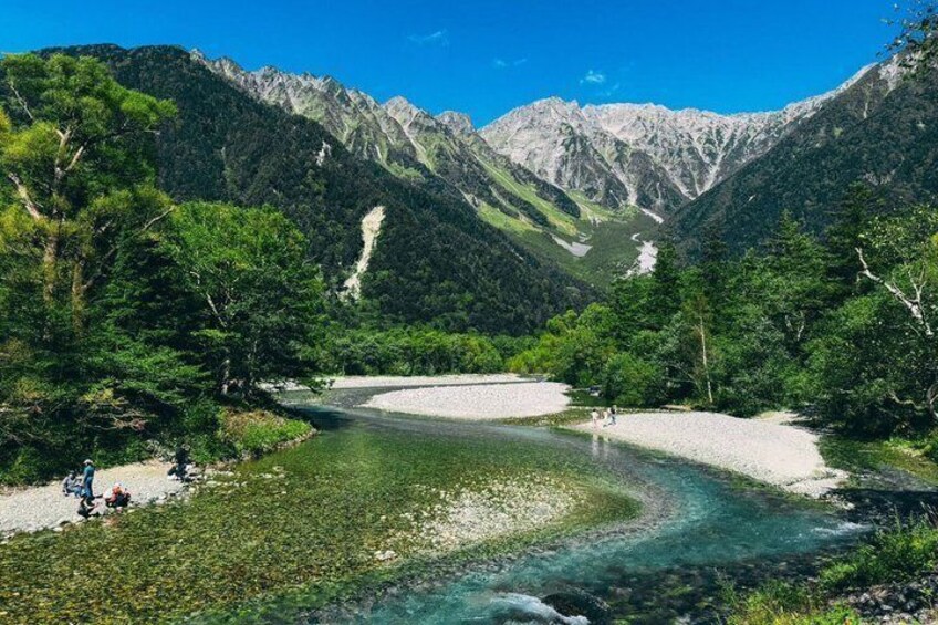 A river winding through a mountainous landscape with dense green forests and rocky mountains in the background. 3