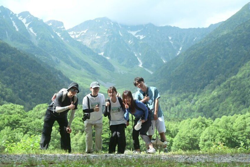 A group of people standing on a path with a mountainous landscape in the background. 1