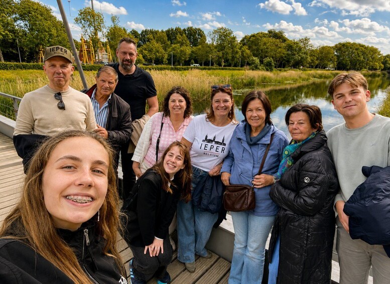 A group of people on a wooden dock by a calm river with trees in the background. 1