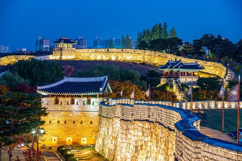 A historic walled city at dusk with illuminated buildings and a traditional pavilion. 3