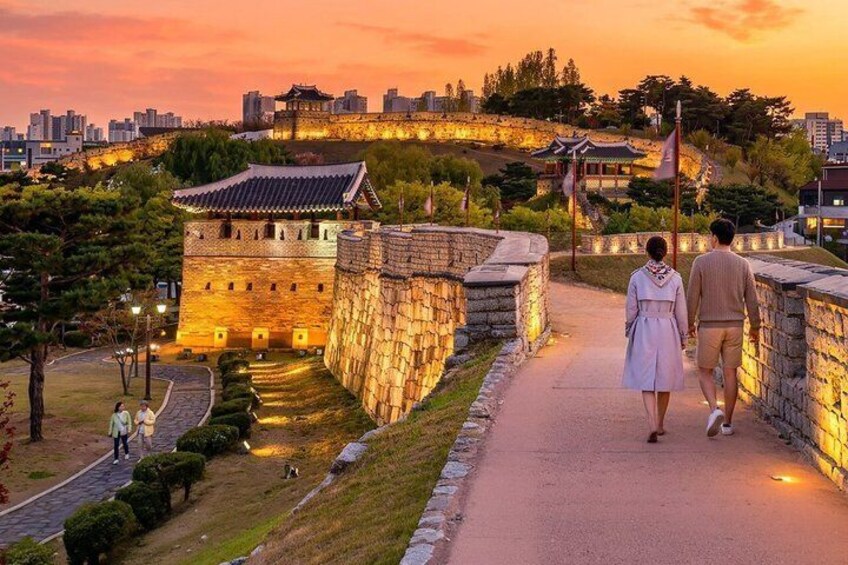 A stone wall pathway with a traditional building in the background. 1