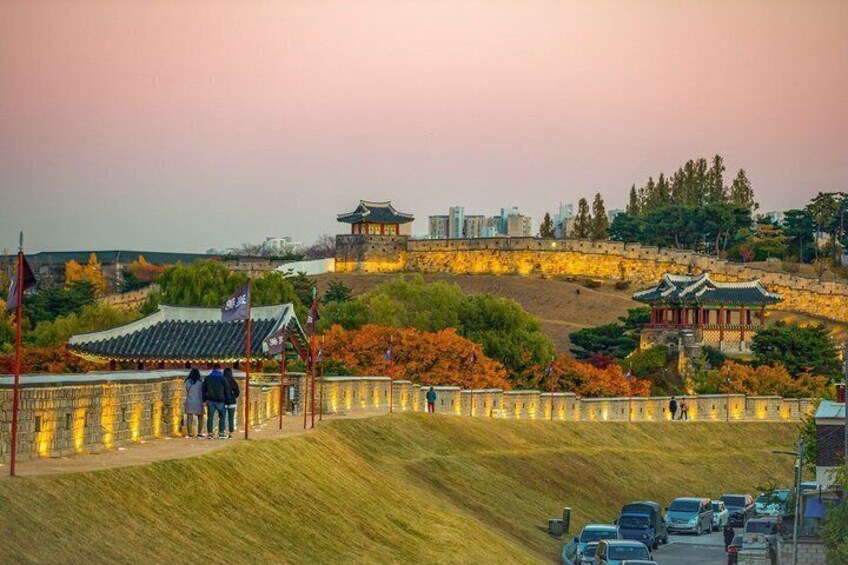 A traditional Korean palace with a stone wall, a pagoda, and autumn foliage. 5