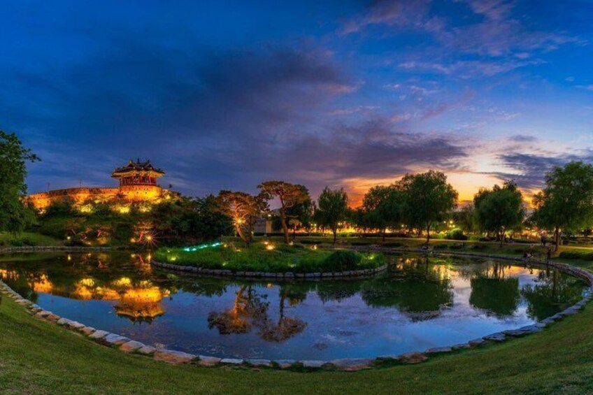 A serene park at dusk with a reflective pond, a traditional pagoda, and a well-maintained lawn. 3