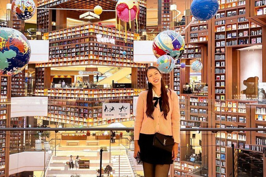 A multi-level bookstore with bookshelves, globes, and a person standing in the center. 2