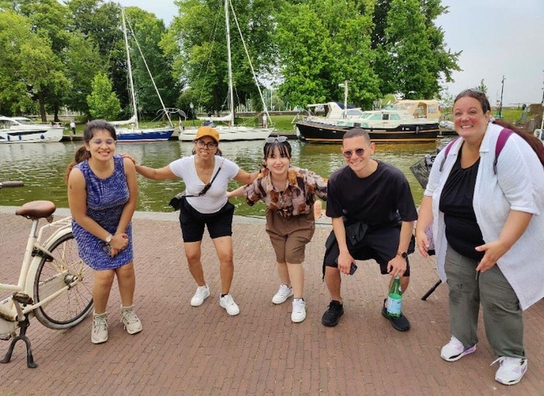 A group of people posing by a waterfront with boats and a bicycle in the background. 5