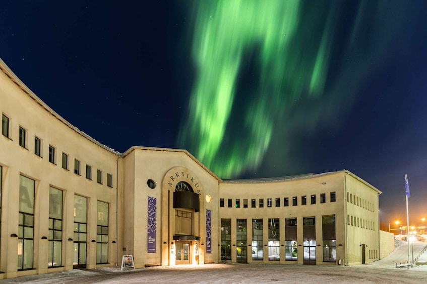 A building with a large arched entrance and multiple windows, under a night sky with green aurora borealis. 3
