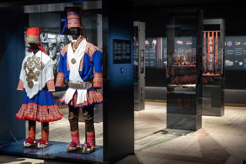 A museum exhibit with traditional costumes and a display case. 5