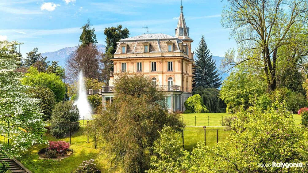 A historic building with a tower, surrounded by lush greenery and a fountain. 3