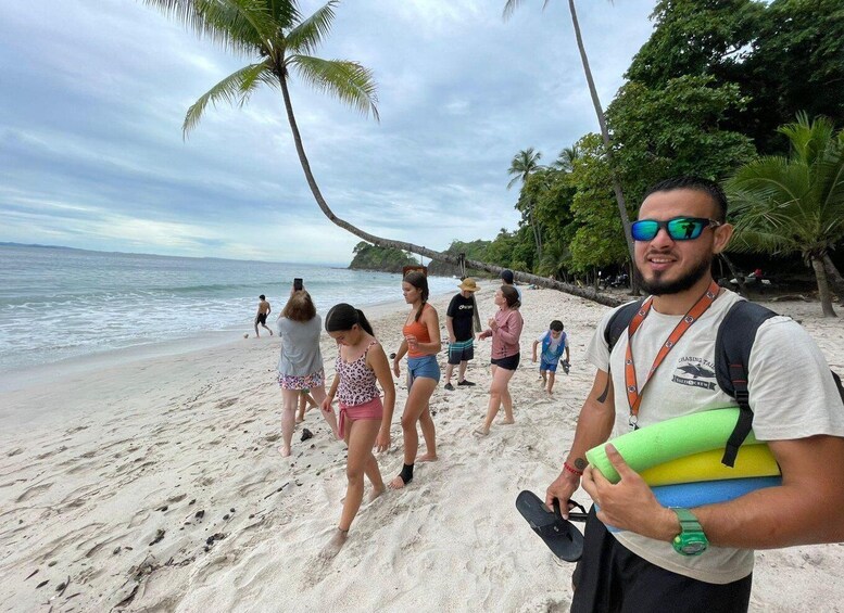 A beach with people walking, palm trees, and the ocean. 1