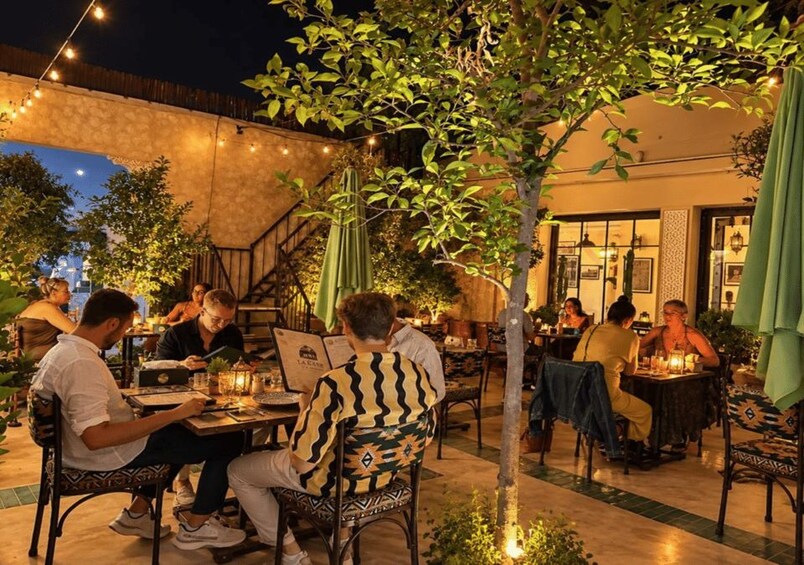 An outdoor dining area with tables and chairs, string lights, and a tree. 5