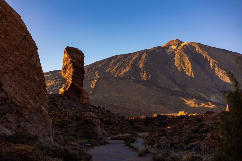 A rugged mountain landscape with a prominent rock formation in the foreground and a large mountain in the background. 1