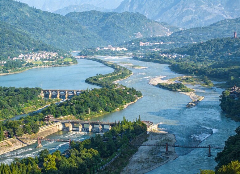 A river winding through a mountainous landscape with a bridge and traditional architecture. 4