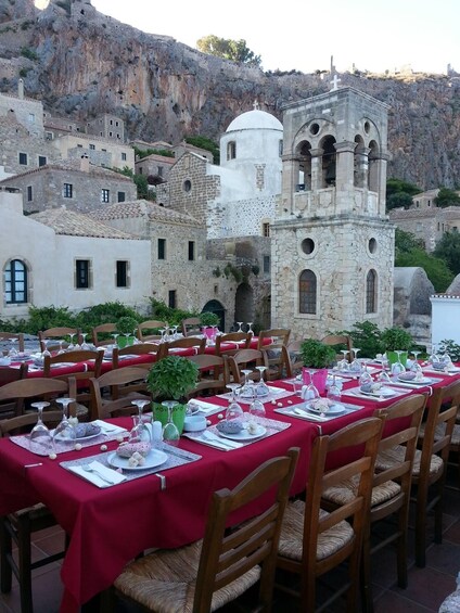 A dining area with tables set for a meal, overlooking a historic church and village. 4