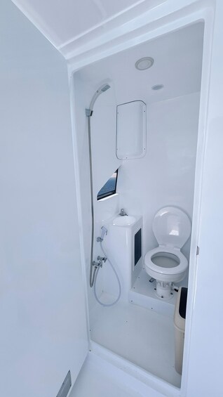 A small, white bathroom with a toilet, sink, and shower. 2