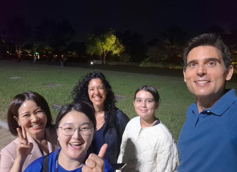 A group of people outdoors at night with artificial lighting. 2