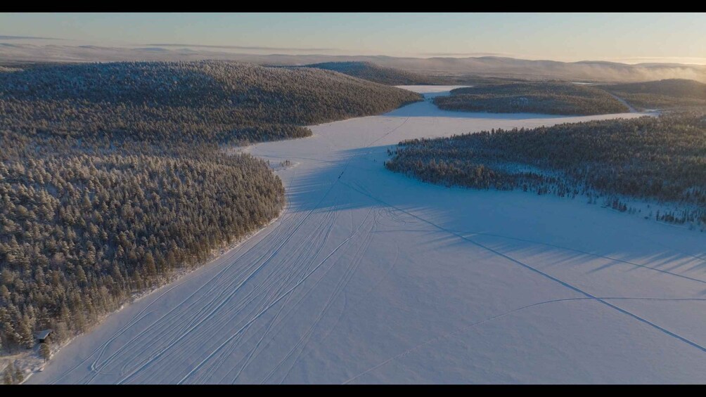 A snow-covered landscape with a frozen lake and dense forests. 2