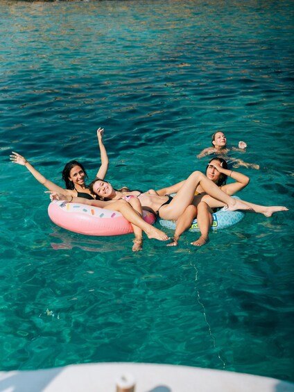 People floating on a clear blue body of water using inflatable rings. 3