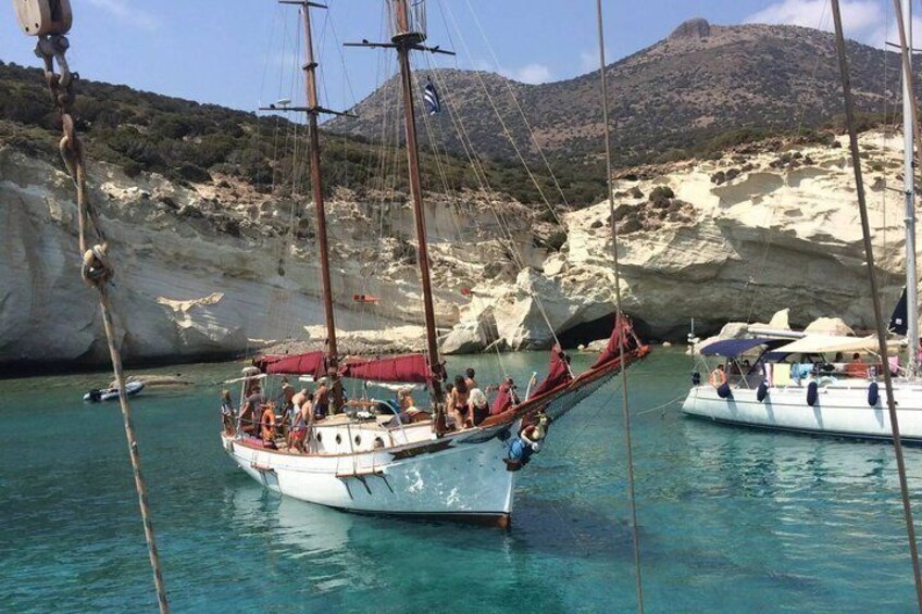 A sailboat docked near a rocky coastline with clear turquoise water. 4