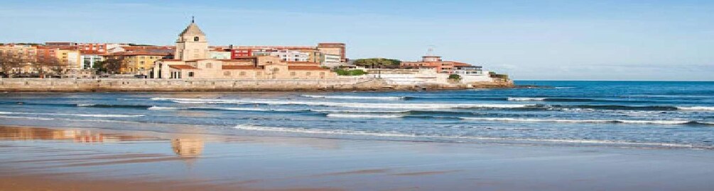 A coastal town with a prominent church, sandy beach, and ocean waves. 3