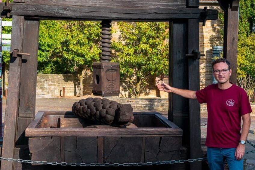 A man standing next to a wooden structure with a large stone and a carved wooden box. 5