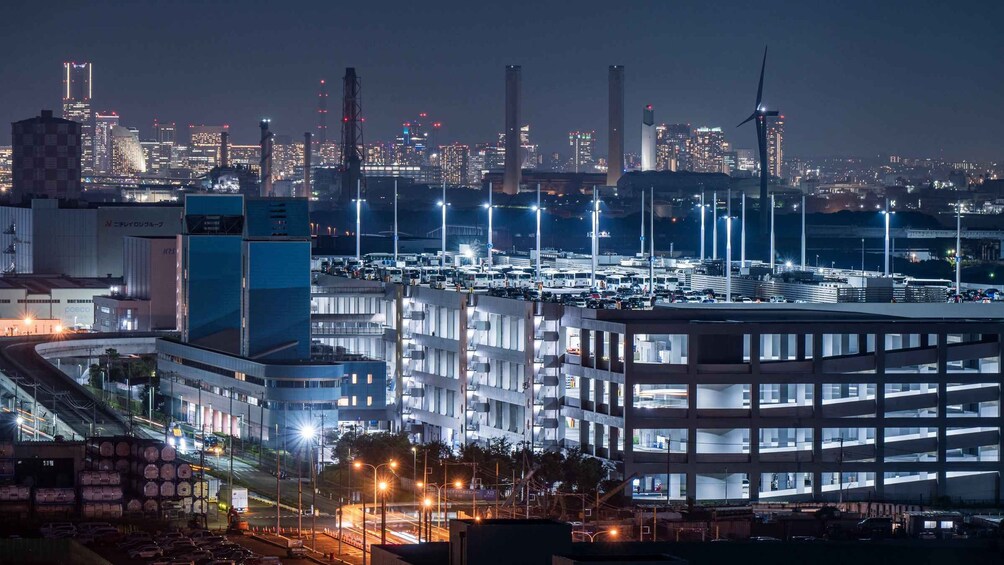 A nighttime cityscape with illuminated buildings, a parking lot, and a bridge. 5