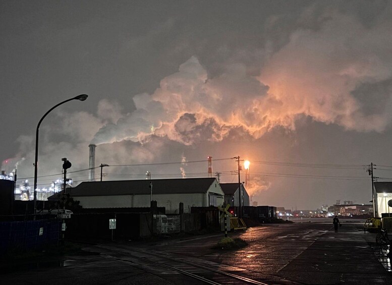 A nighttime scene with a train track, a building with a silo, and a cloudy sky. 4