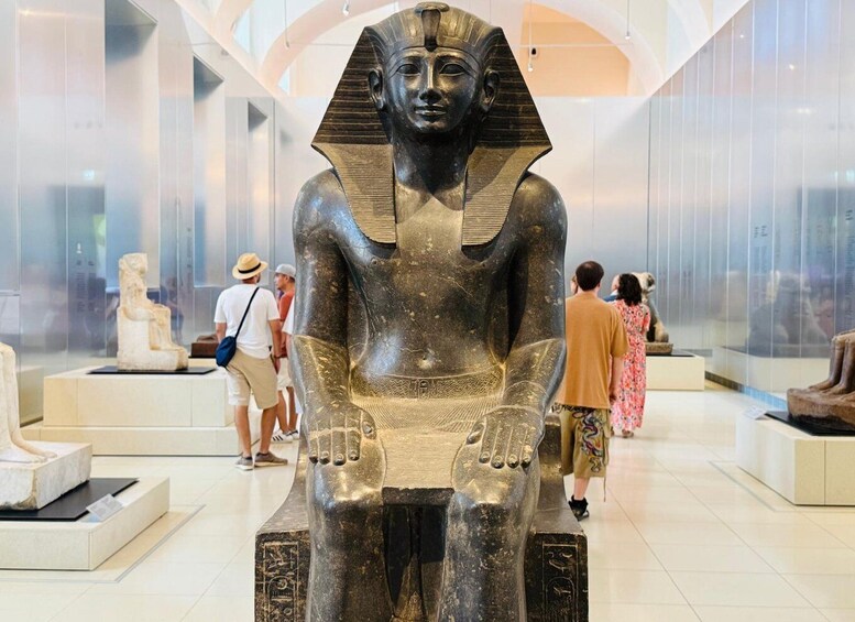 A large Egyptian sarcophagus in a museum with visitors around it. 1