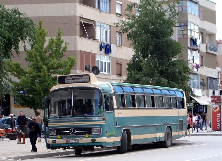A vintage bus with a sign reading 'KABANA APAMA' parked on a street. 5