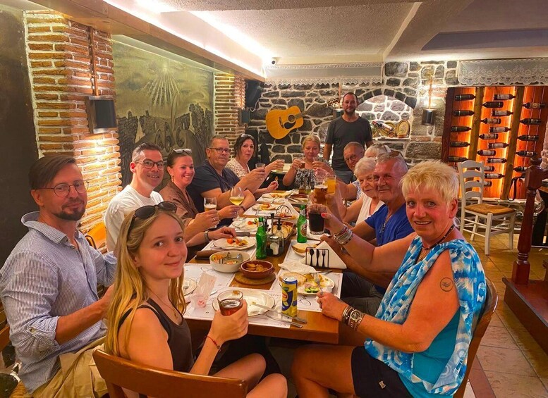 A group of people dining in a restaurant with stone walls and a mural. 2