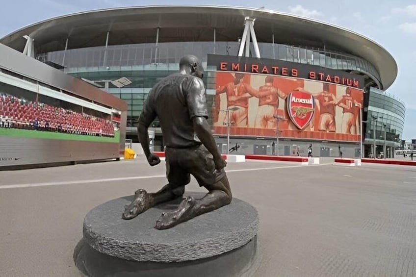 A stadium with a statue of a football player kneeling on a circular base. 5