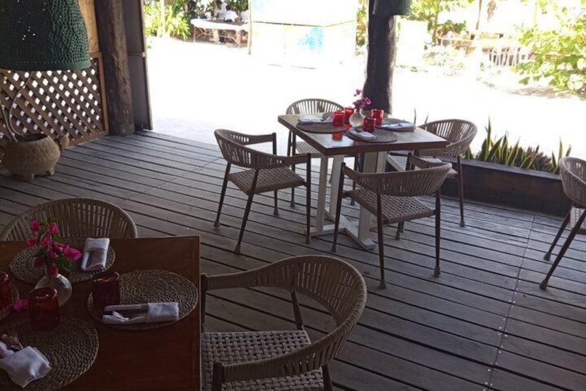 An outdoor wooden deck with wicker furniture and a table set for dining. 2