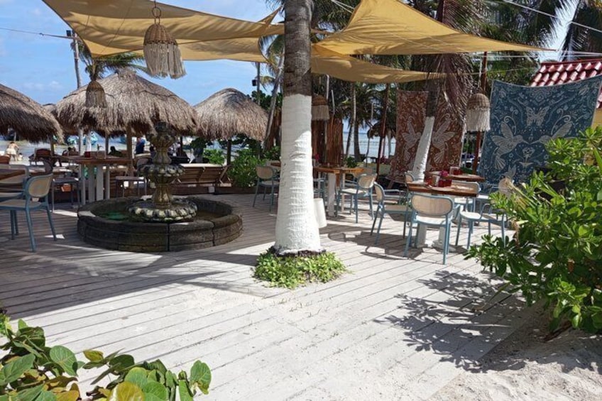 A beachside patio with thatched umbrellas, wooden tables, and chairs. 4