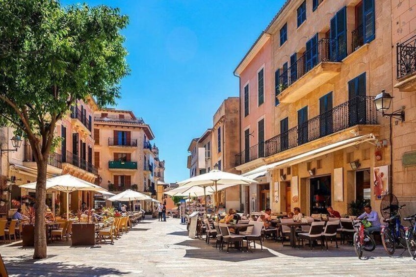 A sunny street with outdoor cafes, trees, and historic buildings. 5