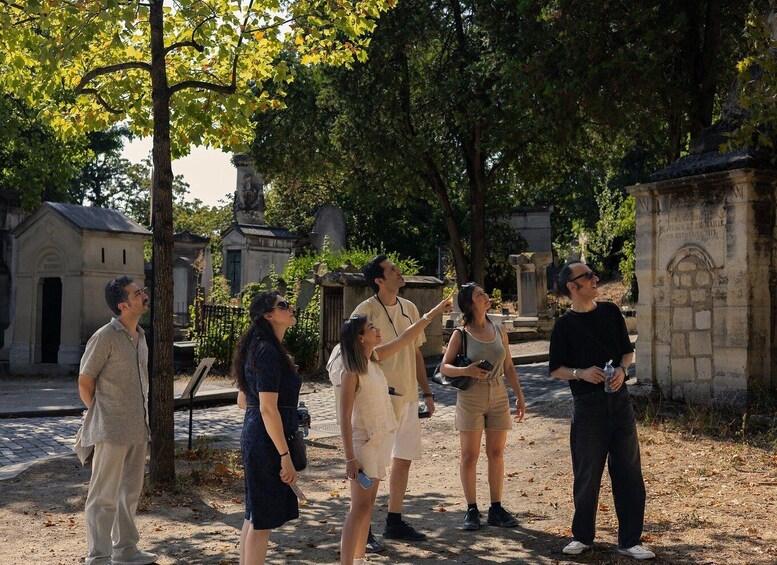 A group of people standing in a cemetery with tombstones and a statue in the background. 1