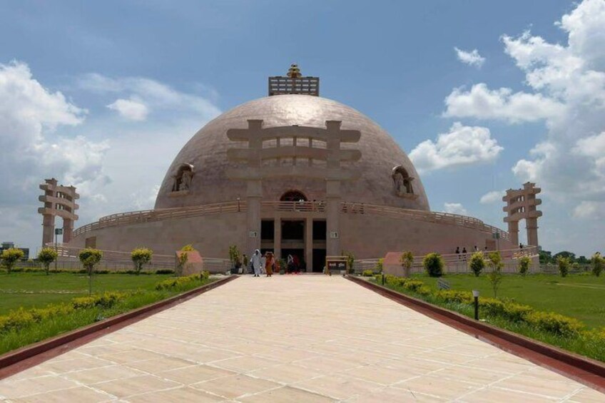 A large, dome-shaped building with a central entrance, surrounded by a paved walkway and greenery. 4