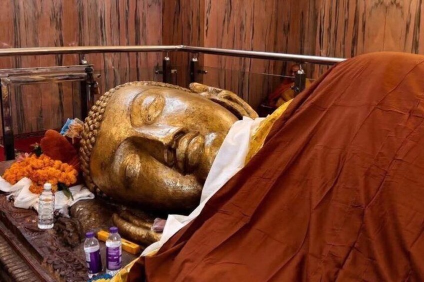 A large golden statue of a reclining figure, possibly a Buddha, with a cloth draped over it. 1