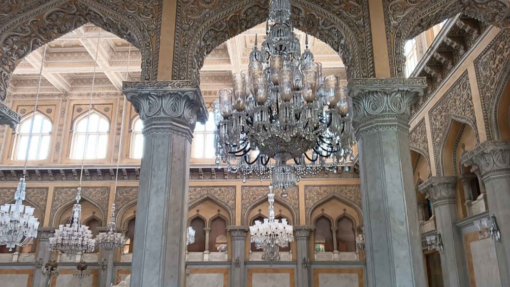 An ornate interior with a large chandelier, arched ceilings, and intricate column designs. 3