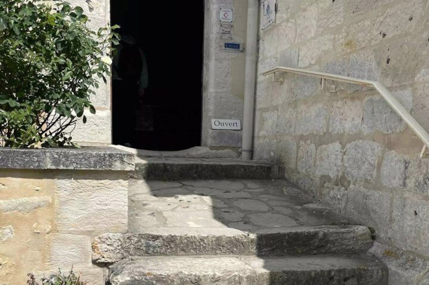 A stone staircase leading to a dark doorway with a sign that reads 'Ouvert'. 5