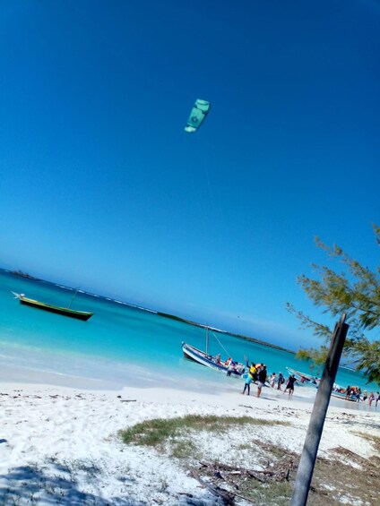 A beach with people, a boat, and a kite. 3