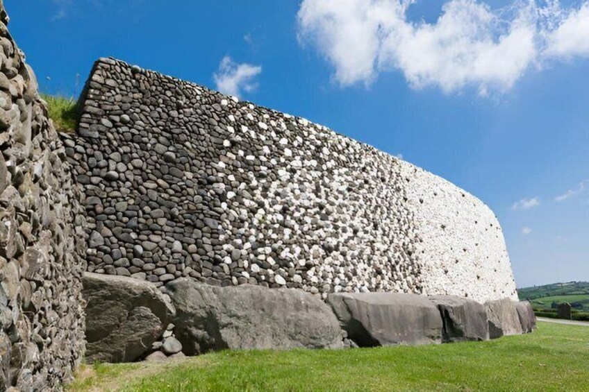 A large stone wall with a mix of large and small stones, set against a clear blue sky. 4