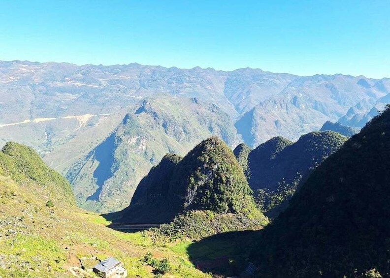 A mountainous landscape with a valley and a small building. 3