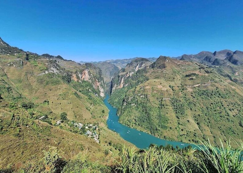 A river valley with steep hills and a clear blue sky. 1