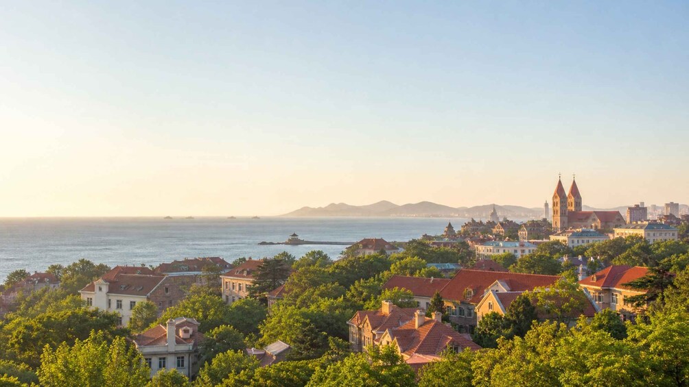 A coastal cityscape with a prominent church, residential buildings, and a clear view of the sea. 1