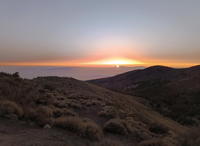 A sunset over a mountainous landscape with sparse vegetation. 5